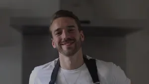 Chef Juan Fortunato wearing an apron, standing in a kitchen, and smiling