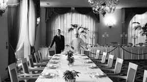Black and White photo of Mattia Cicogna standing in a dining room together with a chef