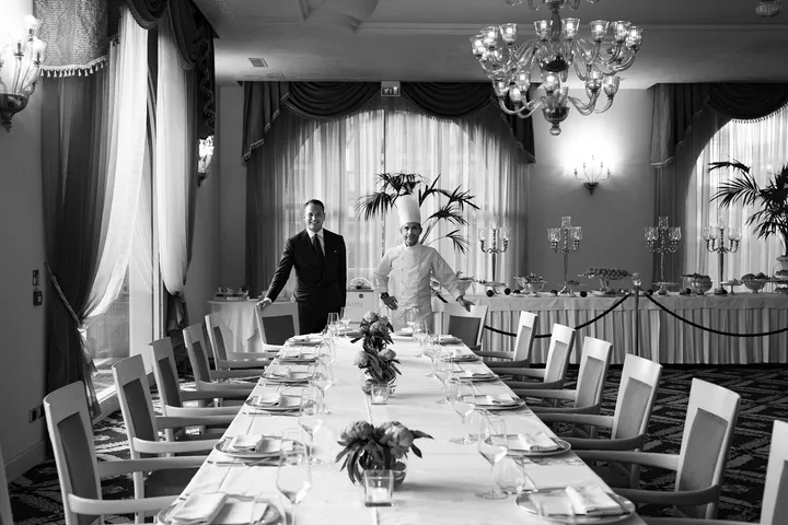 Black and White photo of Mattia Cicogna standing in a dining room together with a chef
