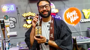 Haidar Hachem holding a bottle of sake and smiling to the camera