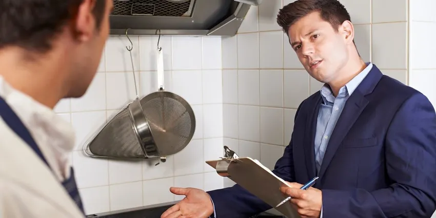 Health Inspector Meeting With Chef In Restaurant Kitchen