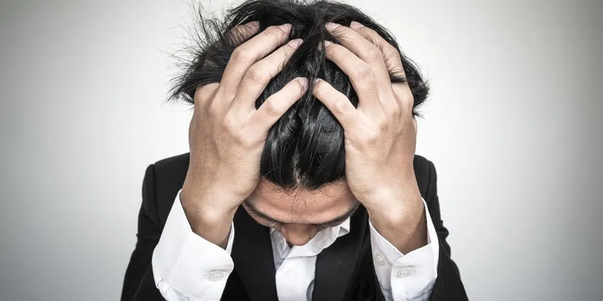 a stressed man with hands on his head
