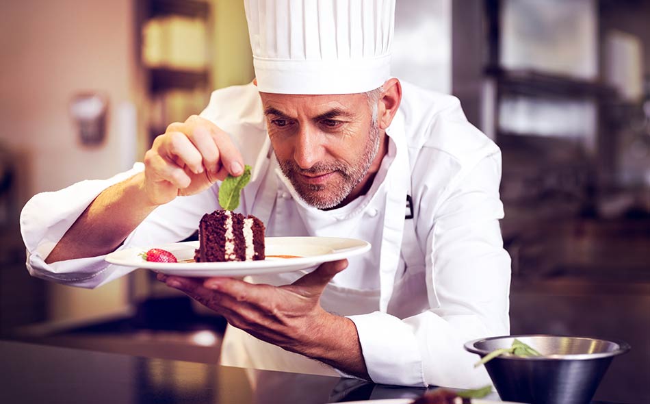 An image of a pastry chef decorating desserts in the kitchen