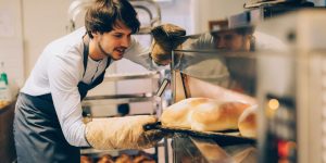 Baker pulling out bread from machine