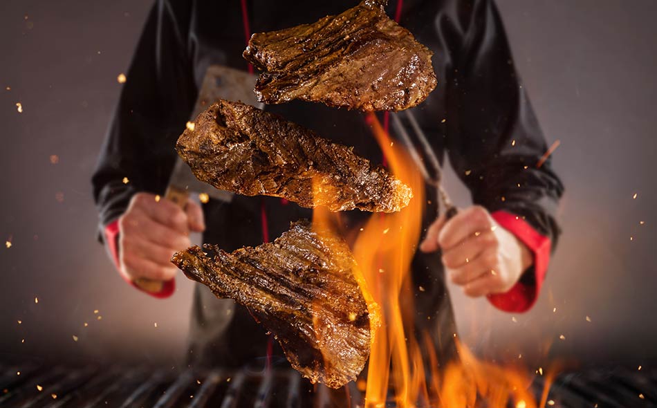 A line cook preparing steaks on a grill