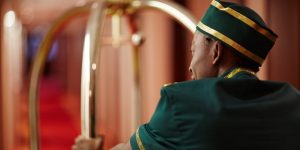 A male porter wearing green pushing a gold trolley