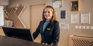 A smiling female receptionist at a reception area wearing a uniform