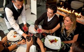 A restaurant server delivers food and wine to diners