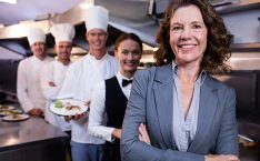Restaurant manager salary: Woman manager standing in front of staff.