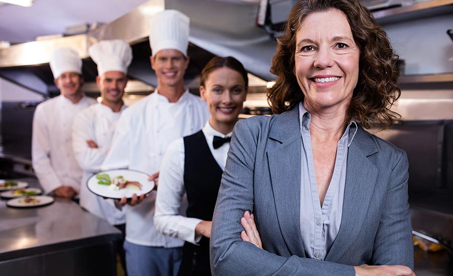 Restaurant manager salary: Woman manager standing in front of staff.