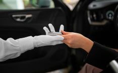 Valet salary: a gloved hand of a valet is handing the car keys to a customer from a vehicle.