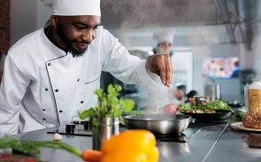 Sous chef job description: an African American man is cooking a steaming hot dish in the restaurant kitchen.