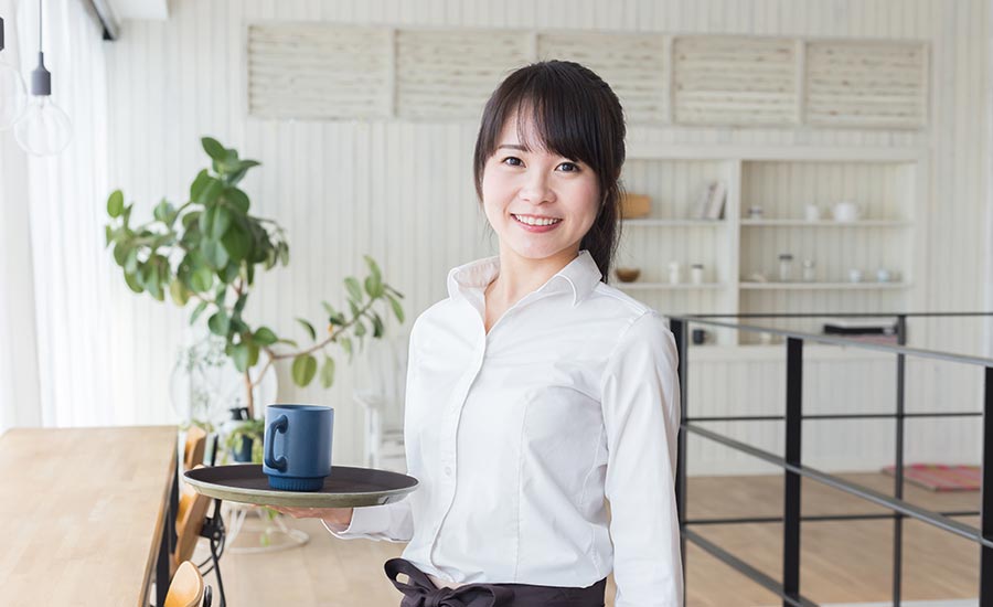 A female Asian kitchen manager smiling and wearing white