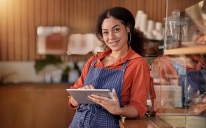 A female restaurant general manager smiling and holding a tablet