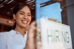 A restaurant worker smiling and holding a sign that says 