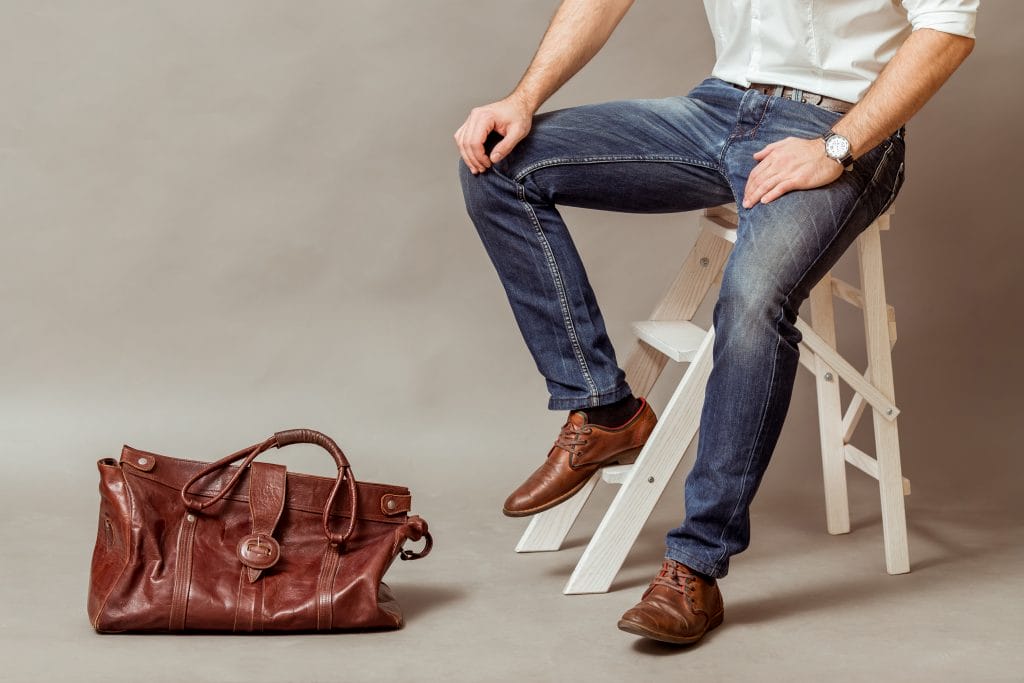 man wearing blue jeans, brown leather belt and shoes