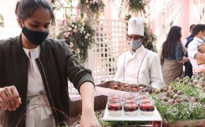A female catering manager wearing a mask fixing the presentation of desserts for a catered event