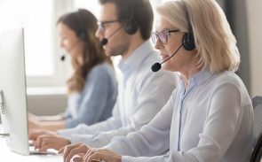 three customer support specialists wearing headsets working at the office