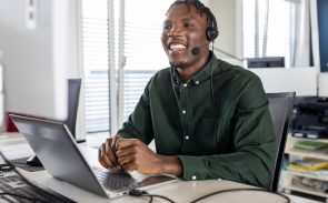 A male Black desktop support engineer smiling and wearing a headset