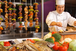 A man preparing meat and vegetables on a grill