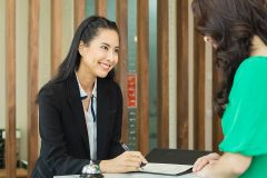 Asian female concierge helping a female guest with her registration