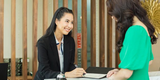 Asian female concierge helping a female guest with her registration