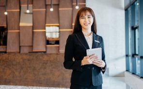 A female Asian hotel manager smiling and holding a tablet