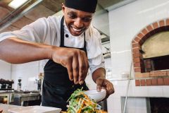 a smiling pantry chef seasoning the salad