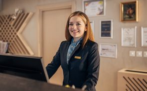 A smiling female receptionist at a reception area wearing a uniform