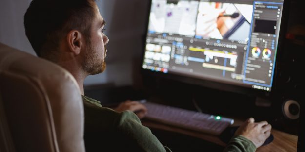 A male video editor editing a video on his desktop