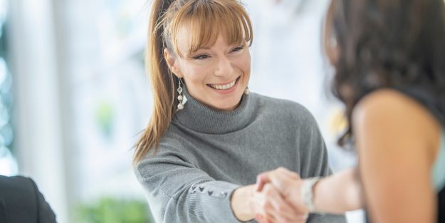 A female field sales (outside sales) representative shaking hands with a client