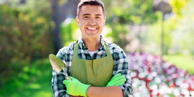 A gardener with crossed arms, one hand holding a trowel