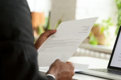 A man, holding a cover letter, is featured in a close-up shot of his arm