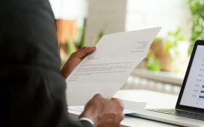 A man, holding a cover letter, is featured in a close-up shot of his arm