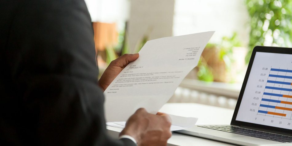 A man, holding a cover letter, is featured in a close-up shot of his arm