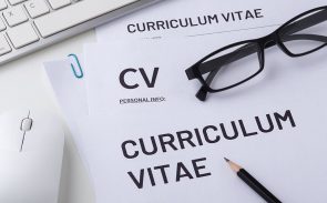 a paper with 'curriculum vitae' heading, computer mouse, keyboard, pen and glasses