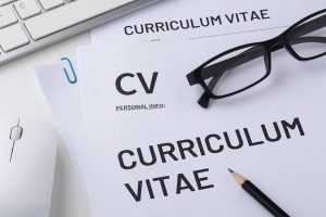 a paper with 'curriculum vitae' heading, computer mouse, keyboard, pen and glasses