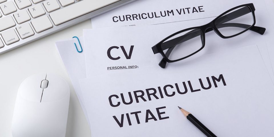 a paper with 'curriculum vitae' heading, computer mouse, keyboard, pen and glasses