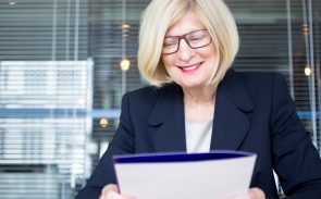 An older female HR Executive smiling while holding a folder