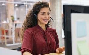 A female sales development representative wearing headphones and working with her desktop computer