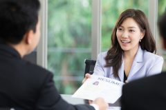 A female applicant handing her resume to two HR professionals