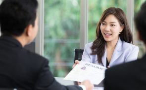 A female applicant handing her resume to two HR professionals
