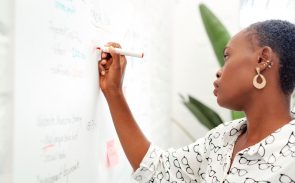 a woman outlining a strategy on a whiteboard