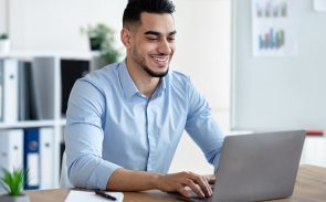 A male employee smiling while typing on his laptop