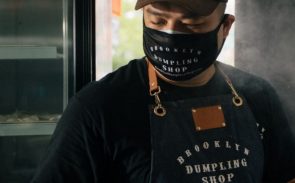 A chef from Brooklyn Dumpling Shop wearing a face mask and a cap