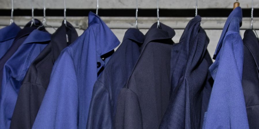 a bunch of blue shirts on a rack