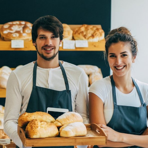 Two bakers standing in front of their bread selections