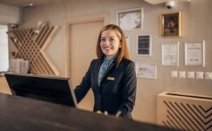 A smiling female receptionist at a reception area wearing a uniform