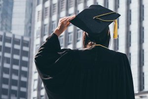 Back view of a woman in graduation attire holding her cap