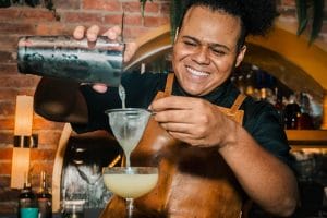 Male Bartender filtering a margarita drink